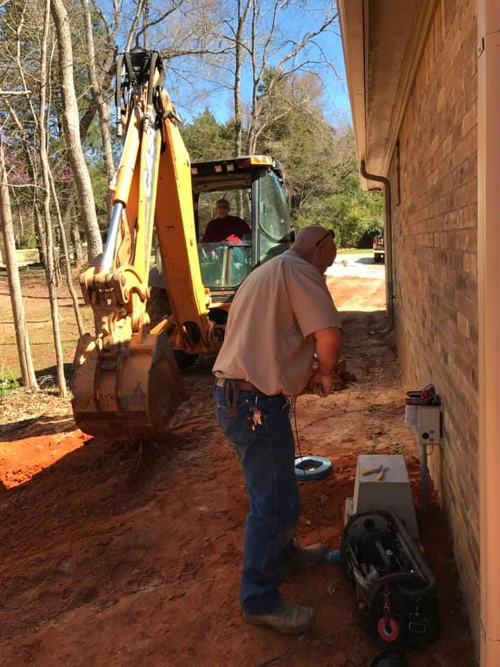 A man is standing in front of a yellow excavator.