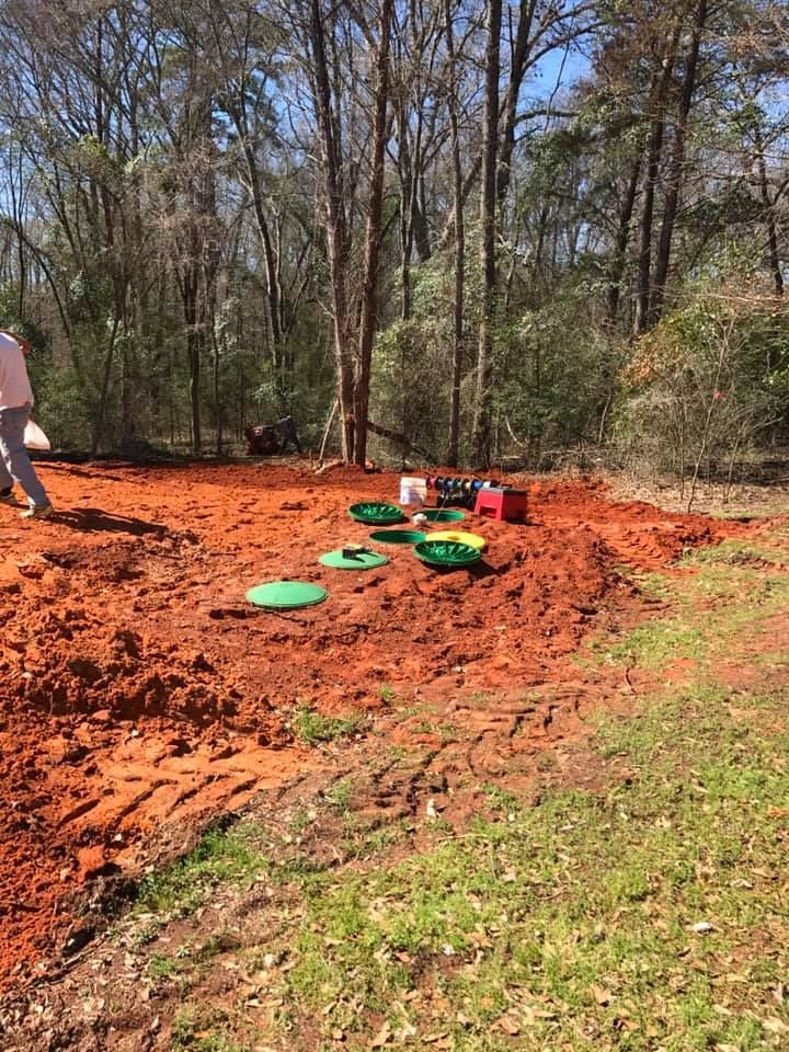 A man is standing in the middle of a dirt field.