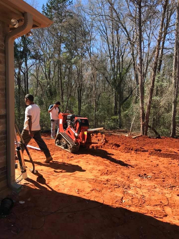 A man is standing next to a bulldozer in a dirt field.