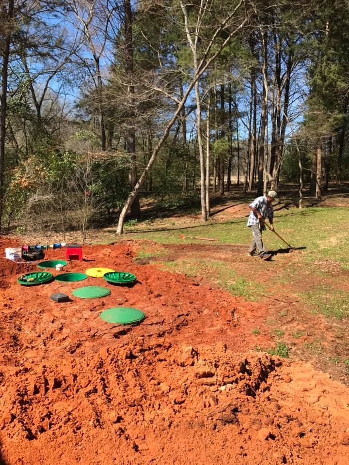 A man is digging in the dirt in a yard.