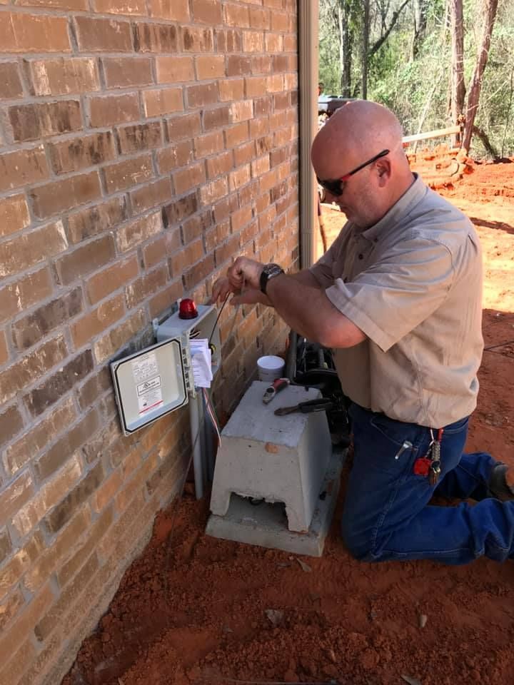 A man is kneeling down working on a brick wall.