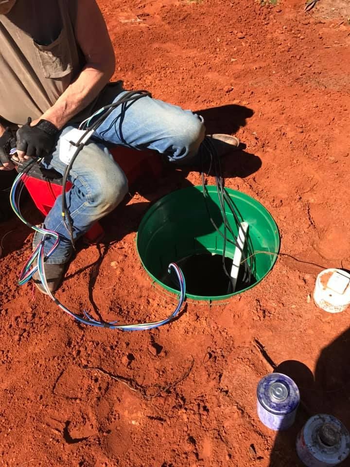 A man is kneeling in the dirt next to a green bucket