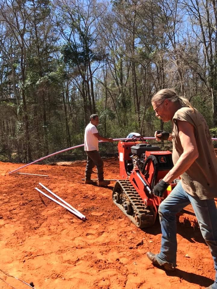 Two men are working on a tractor in the dirt.