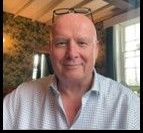 A man wearing glasses and a white lab coat with the name john on it