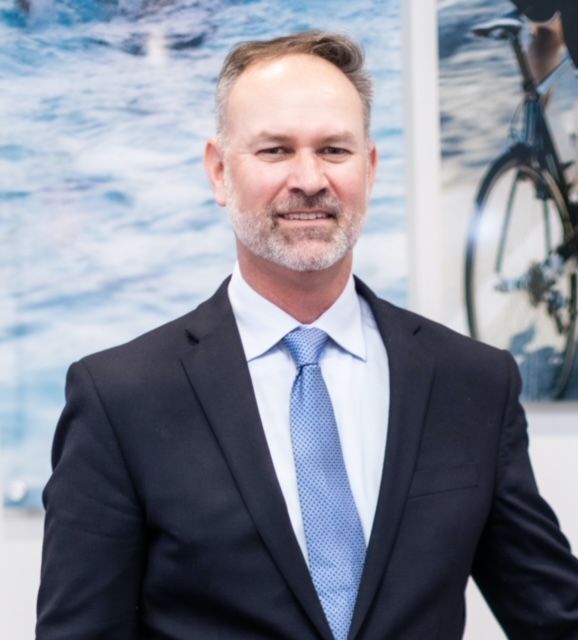A man wearing glasses and a white lab coat with the name john on it