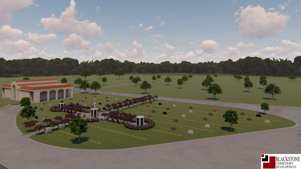 An aerial view of a cemetery with a mausoleum, rows of headstones, trees, and a grassy landscape.