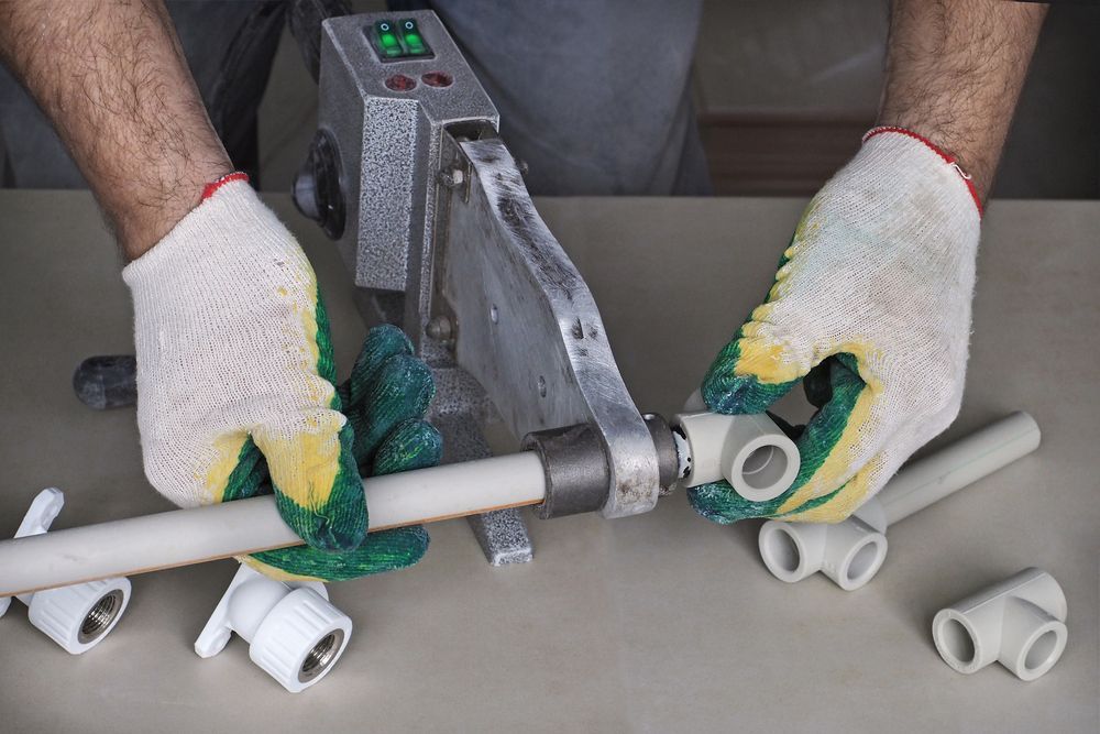 Person Using a Pipe Fusion Tool to Connect White Plastic — Harwood Plumbing & Gasfitting Pty Ltd in Alawa, NT