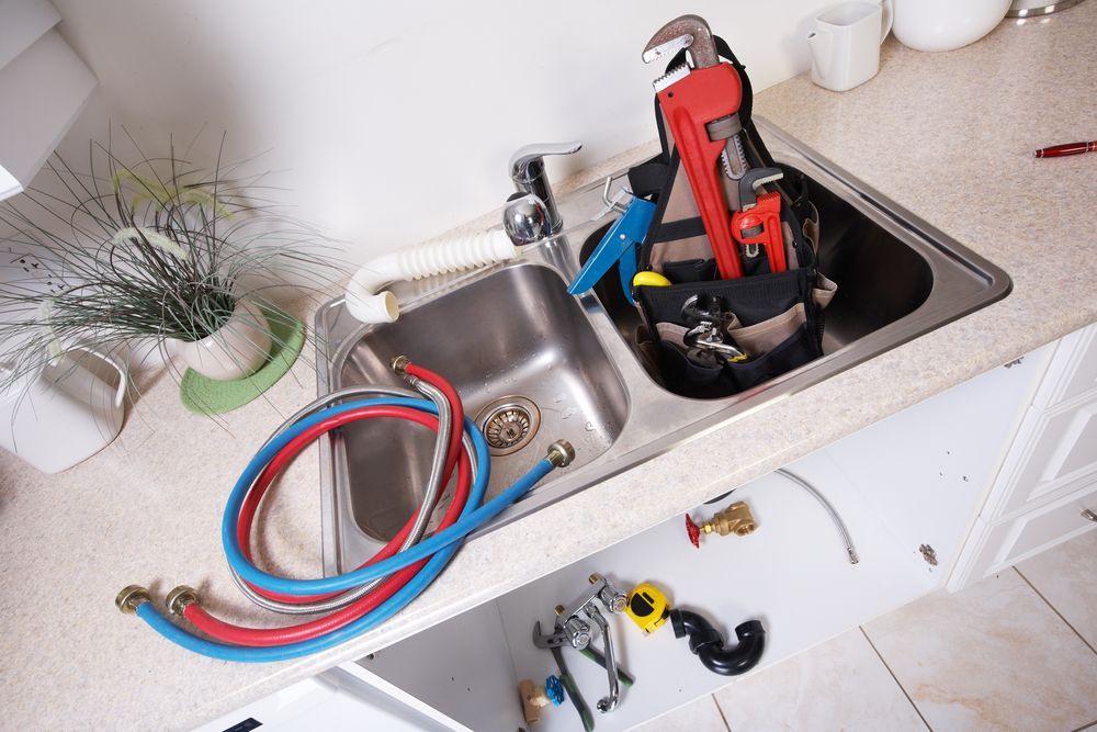 Plumber's Tools in A Kitchen Sink with Hoses Coiled — Harwood Plumbing & Gasfitting Pty Ltd in Alawa, NT
