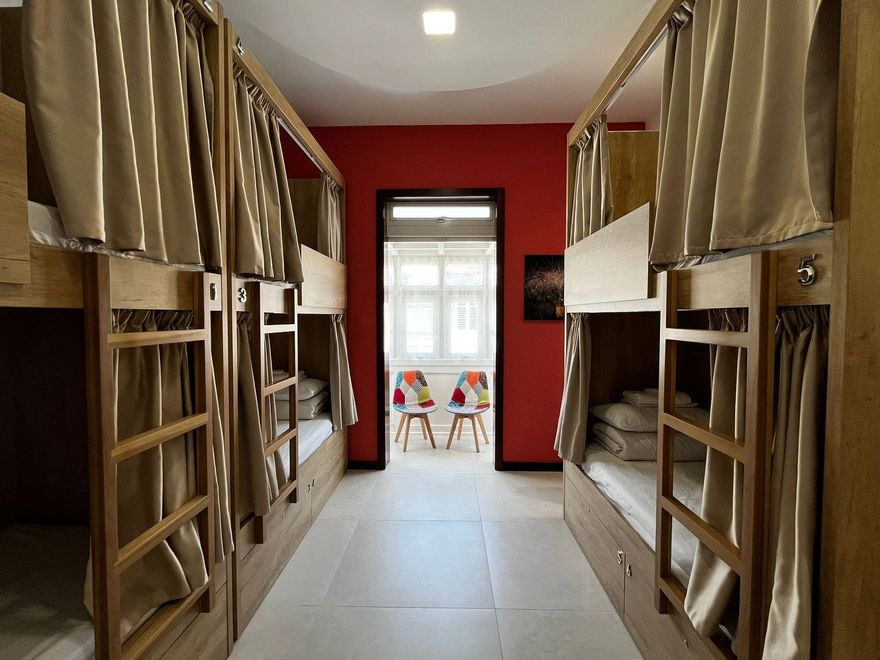 Dormitory-style room with two rows of bunk beds, red accent wall, chairs & a Maltese Balcony. Dorm is located on a female-only corridor.