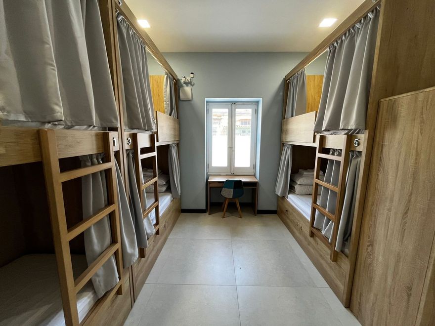 Dorm room with two rows of wooden bunk beds and a desk by a window in the center, on a female-only corridor.  