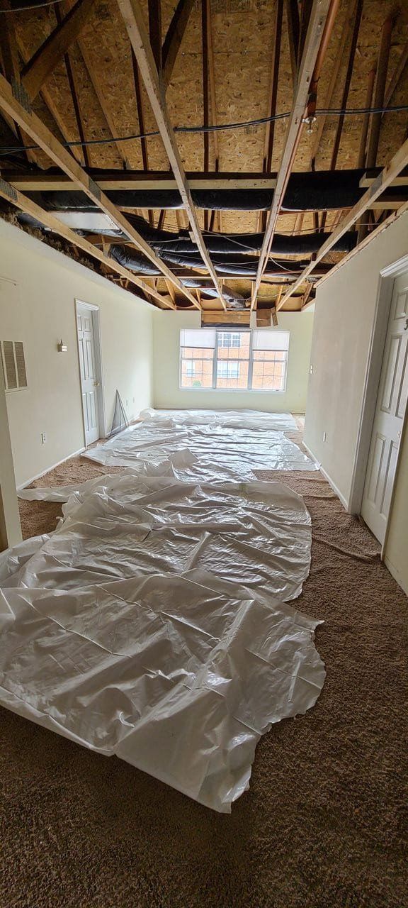 An empty room with a plastic tarp on the floor.