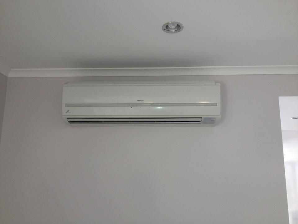 A White Air Conditioner is Mounted on a White Wall — Legit Air Conditioning in Garbutt, QLD
