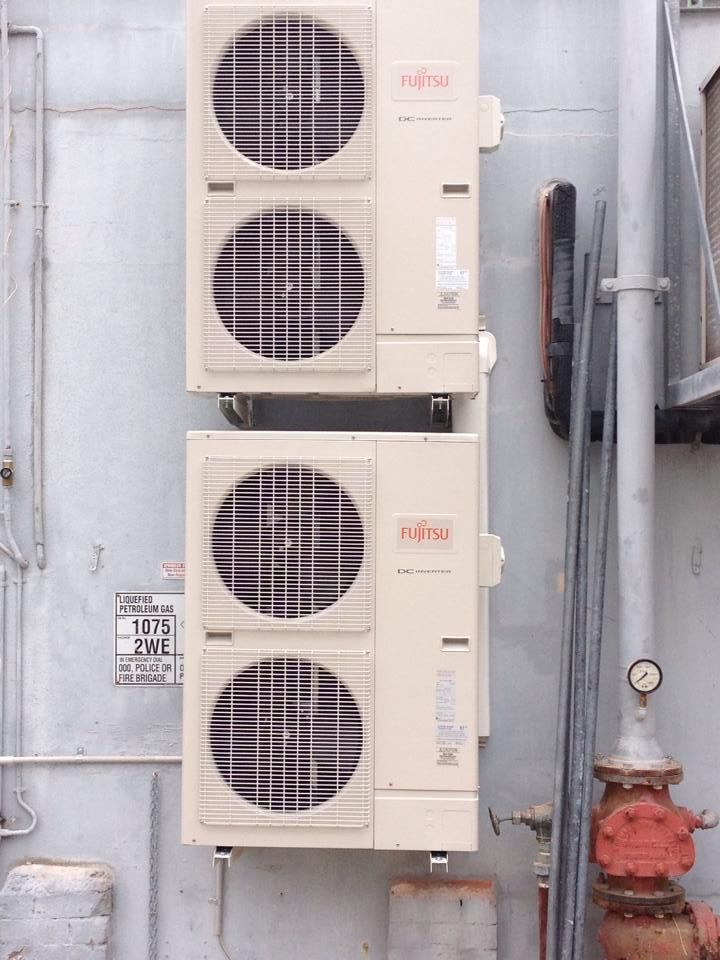 Three Air Conditioners Are Stacked on Top of Each Other on the Side of a Building — Legit Air Conditioning in Garbutt, QLD