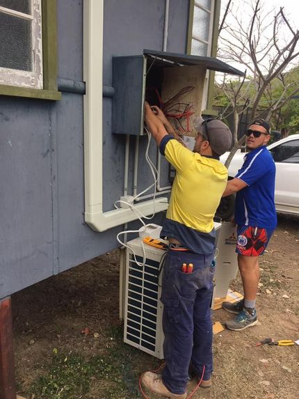 Two Men Are Working on an Air Conditioner Outside of a Building — Legit Air Conditioning in Garbutt, QLD