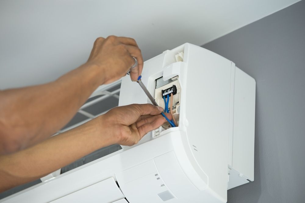 A Person is Fixing an Air Conditioner With a Screwdriver — Legit Air Conditioning in Magnetic Island, QLD
