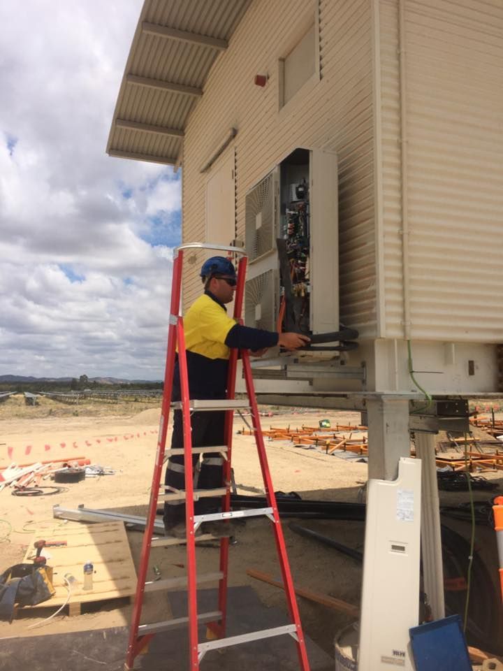A Man on a Ladder Working on a Building — Legit Air Conditioning in Garbutt, QLD