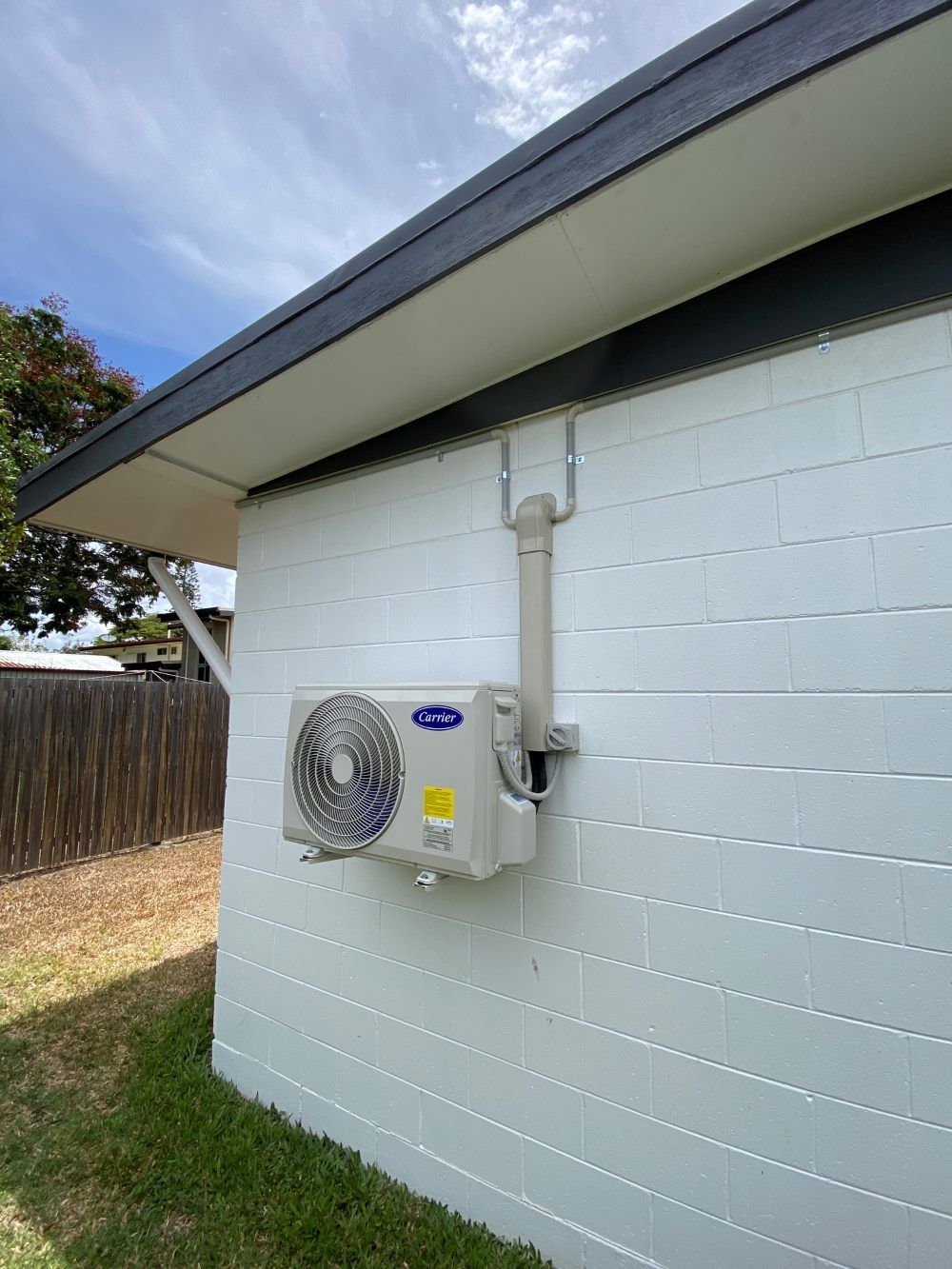 A White Brick Building With a Fan on the Side of It — Legit Air Conditioning in Garbutt, QLD
