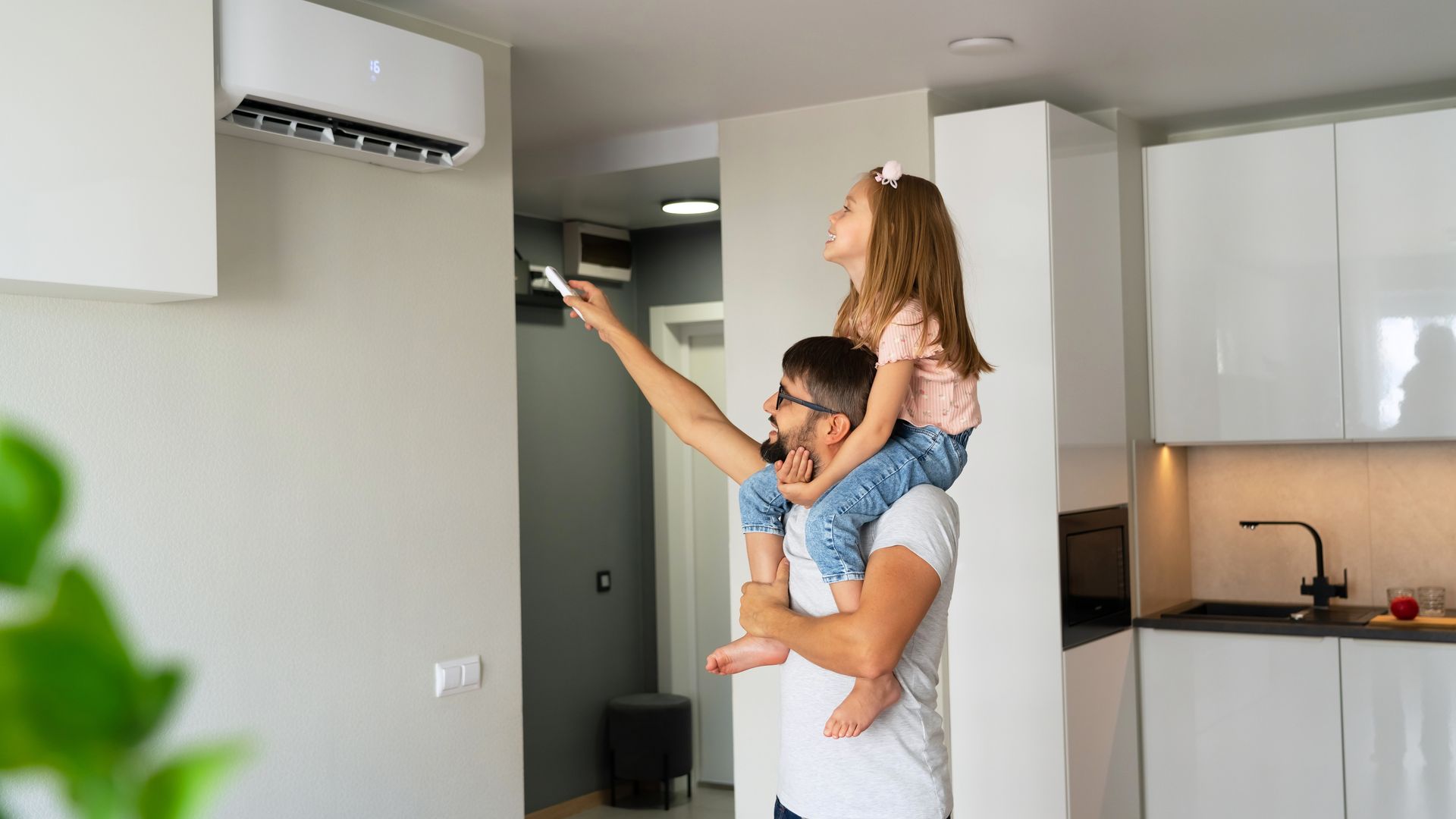 A Man is Holding a Little Girl on His Shoulders While Adjusting the Air Conditioner — Legit Air Conditioning in Garbutt, QLD