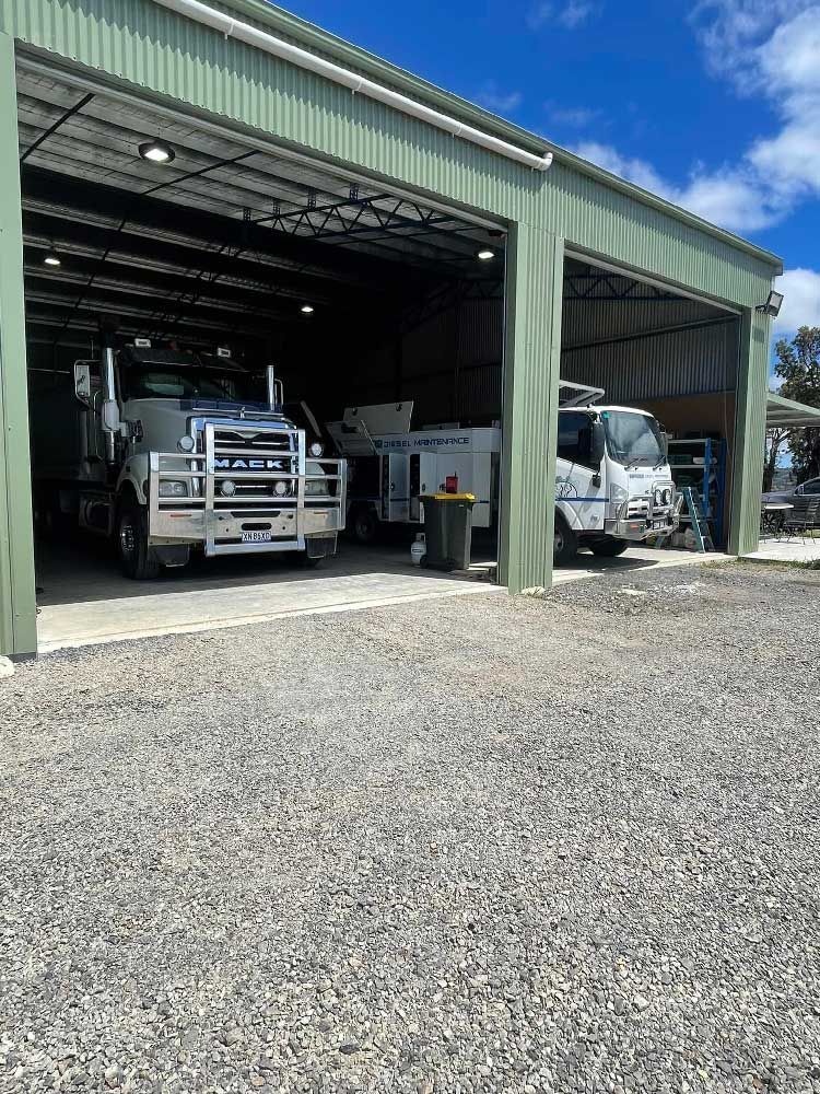 Two Large Trucks Parked Inside a Mechanic's Garage — Superior Diesel Maintenance in Westdale, NSW