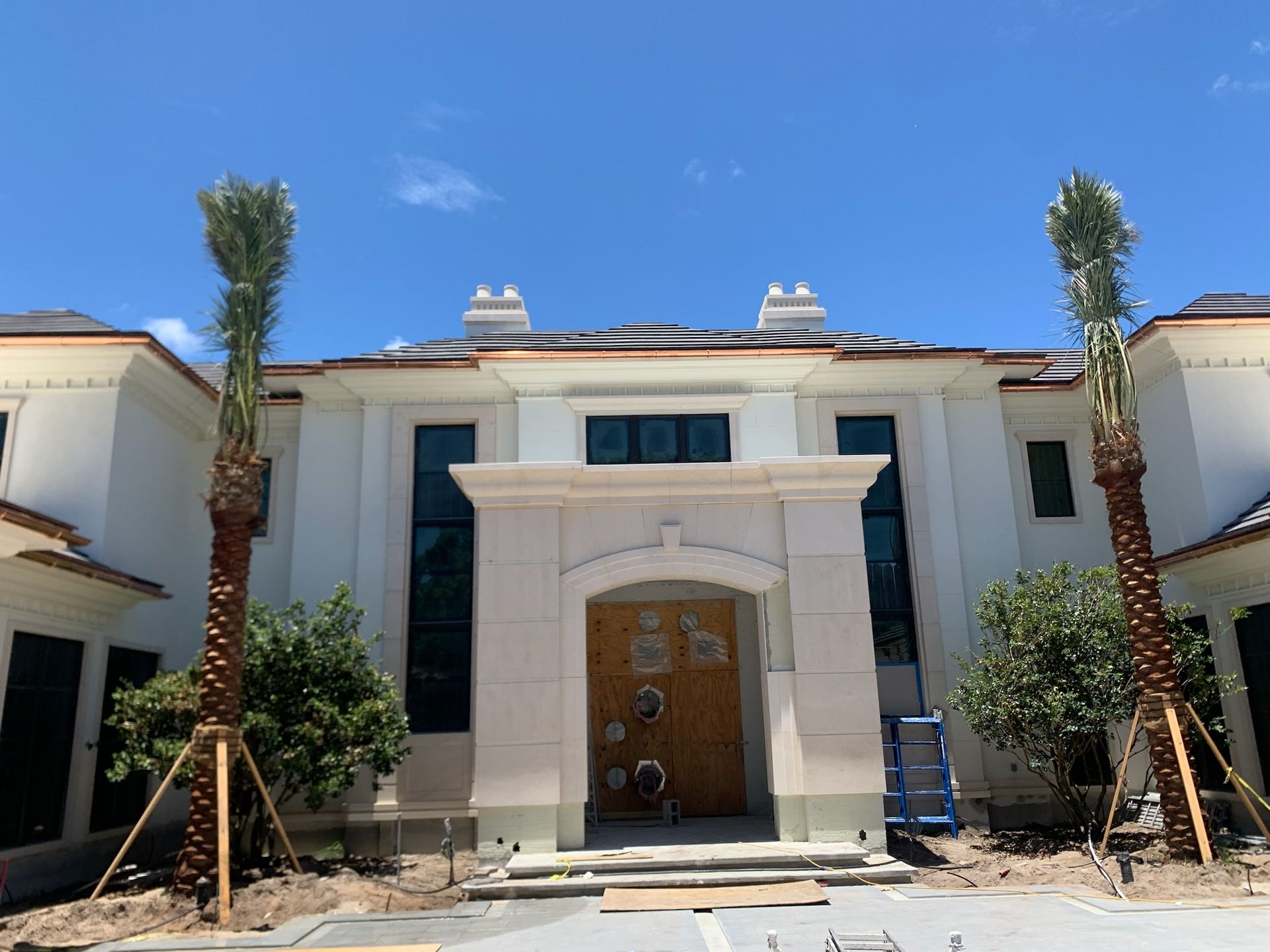 Beige rain gutter on a yellow stucco house corner against a blue sky.