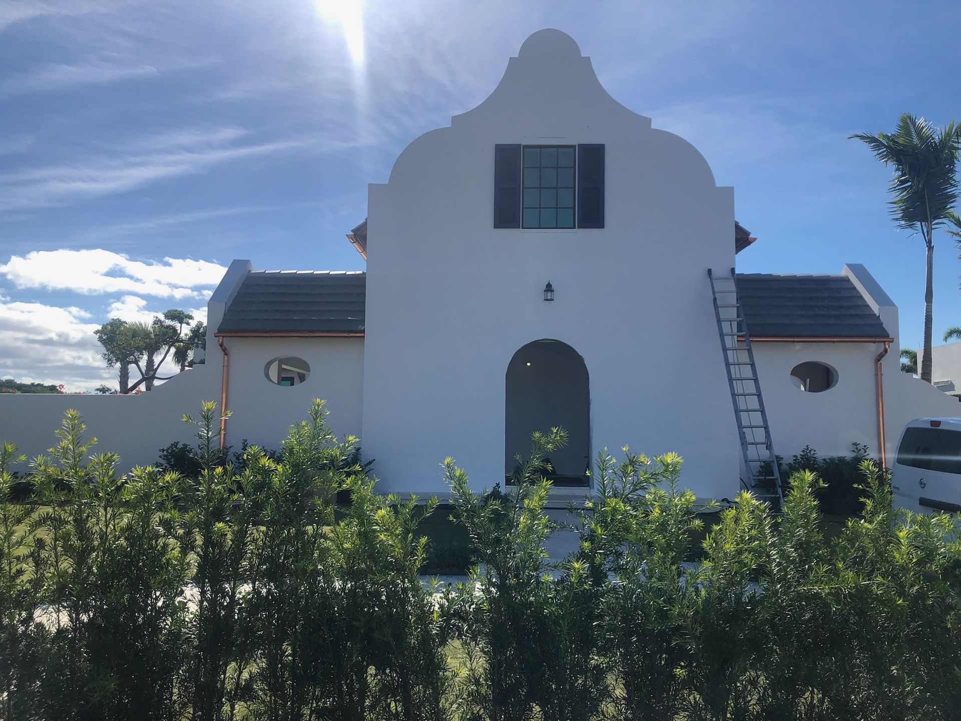 Red wooden siding with a vertical, silver pipe attached by a clamp.