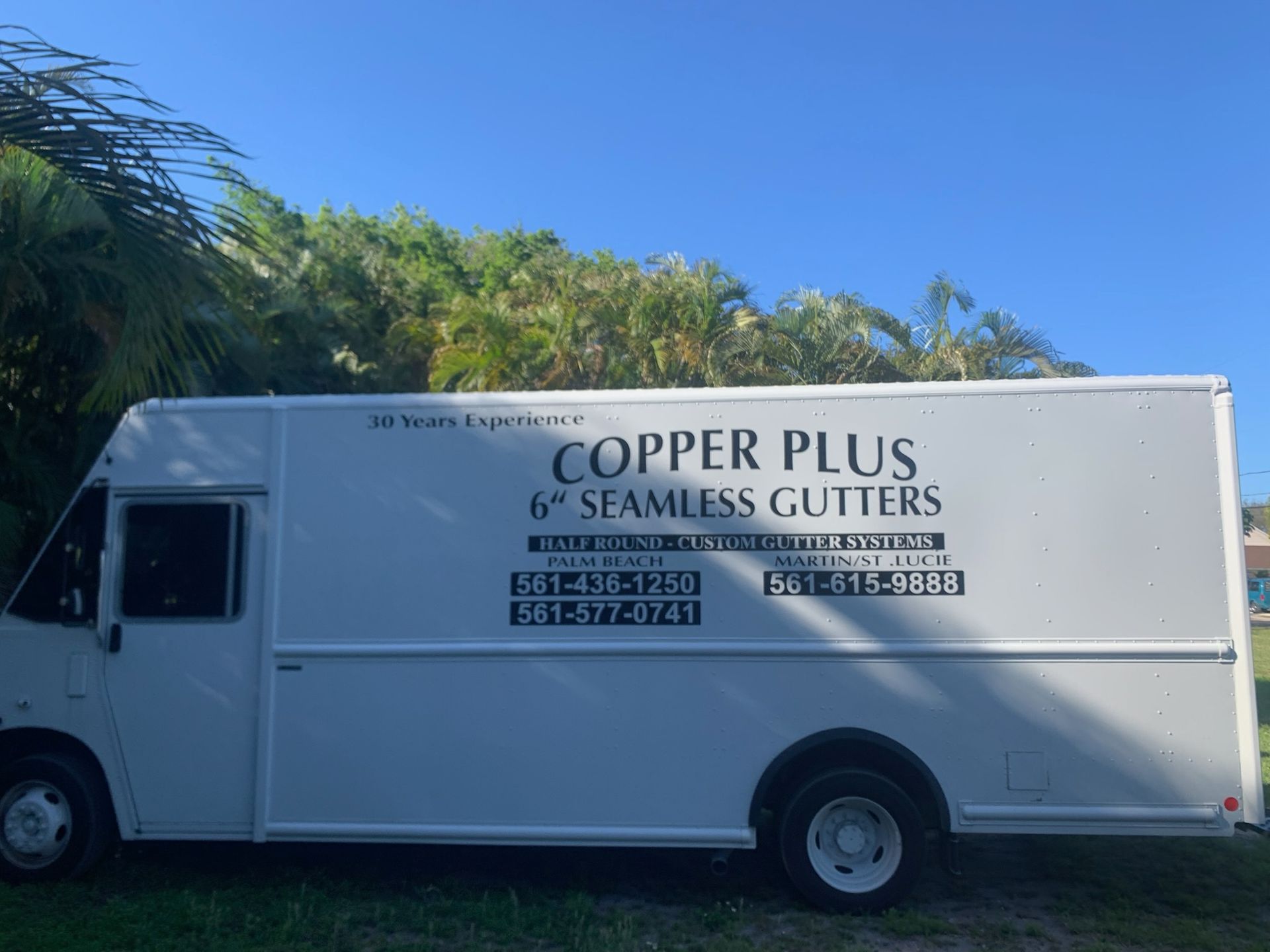 Brown corrugated metal roof with brown gutters, against a blue sky, autumn leaves visible.