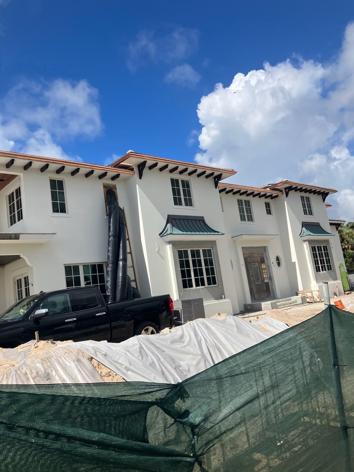 Person installing black rain gutter on a roof's edge, holding it with both hands.
