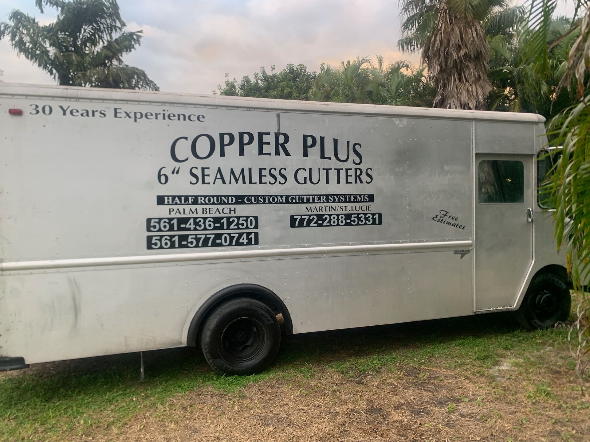 White rain gutter and downspout attached to a white building under a blue sky.