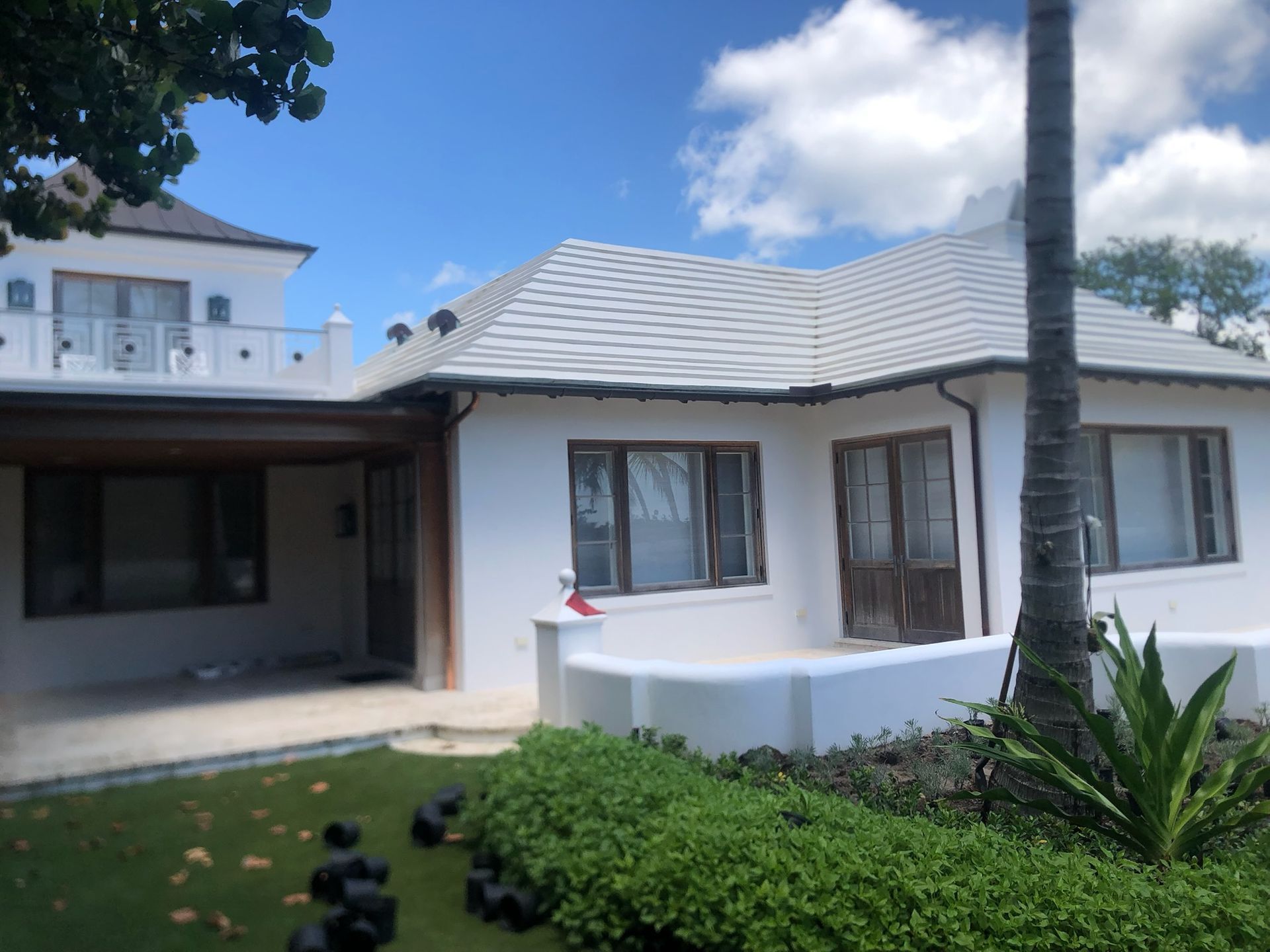 Yellow building facade with green gutter and downspout, window. Blue sky.