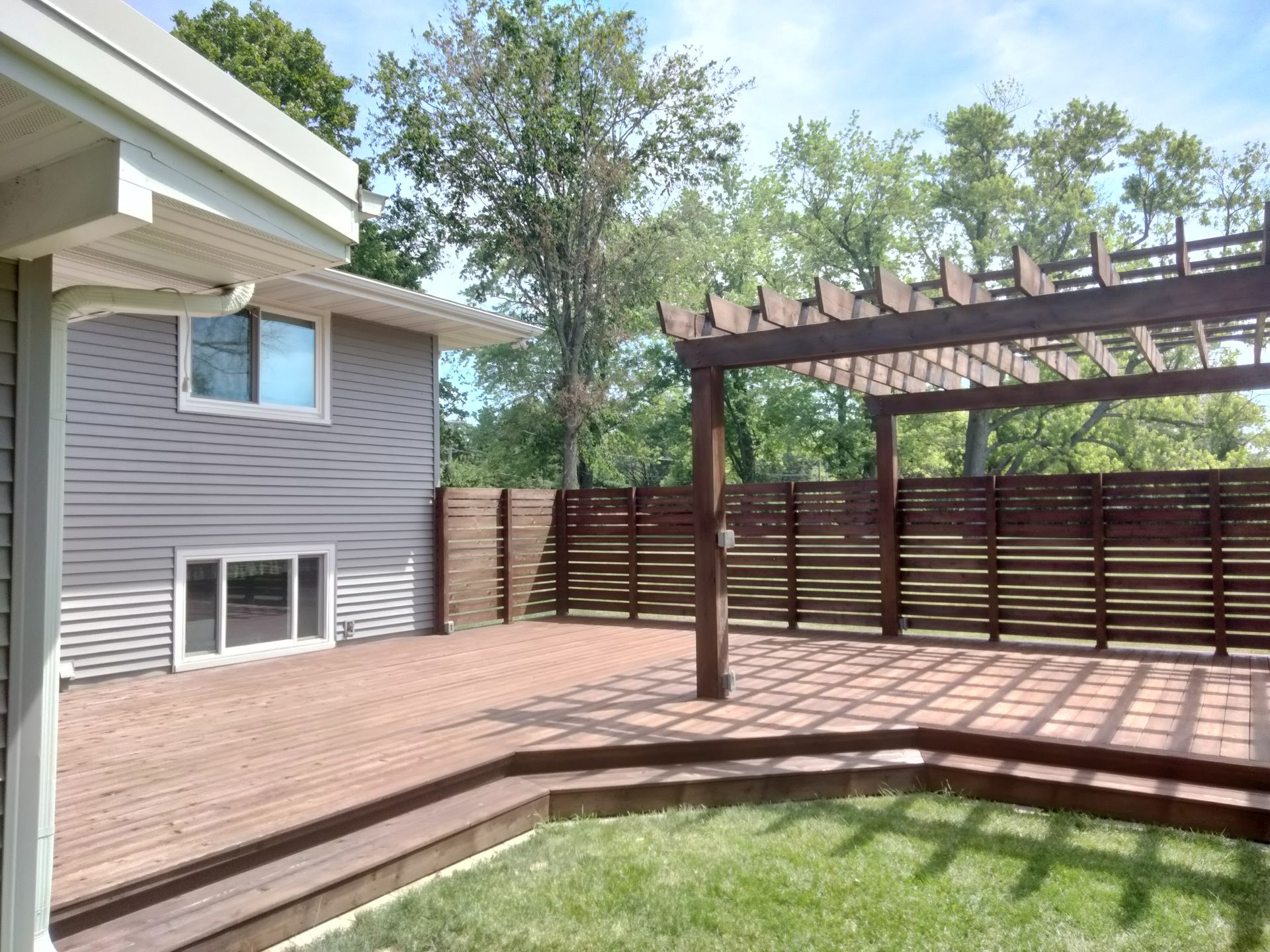 A house with a deck and a pergola in the backyard