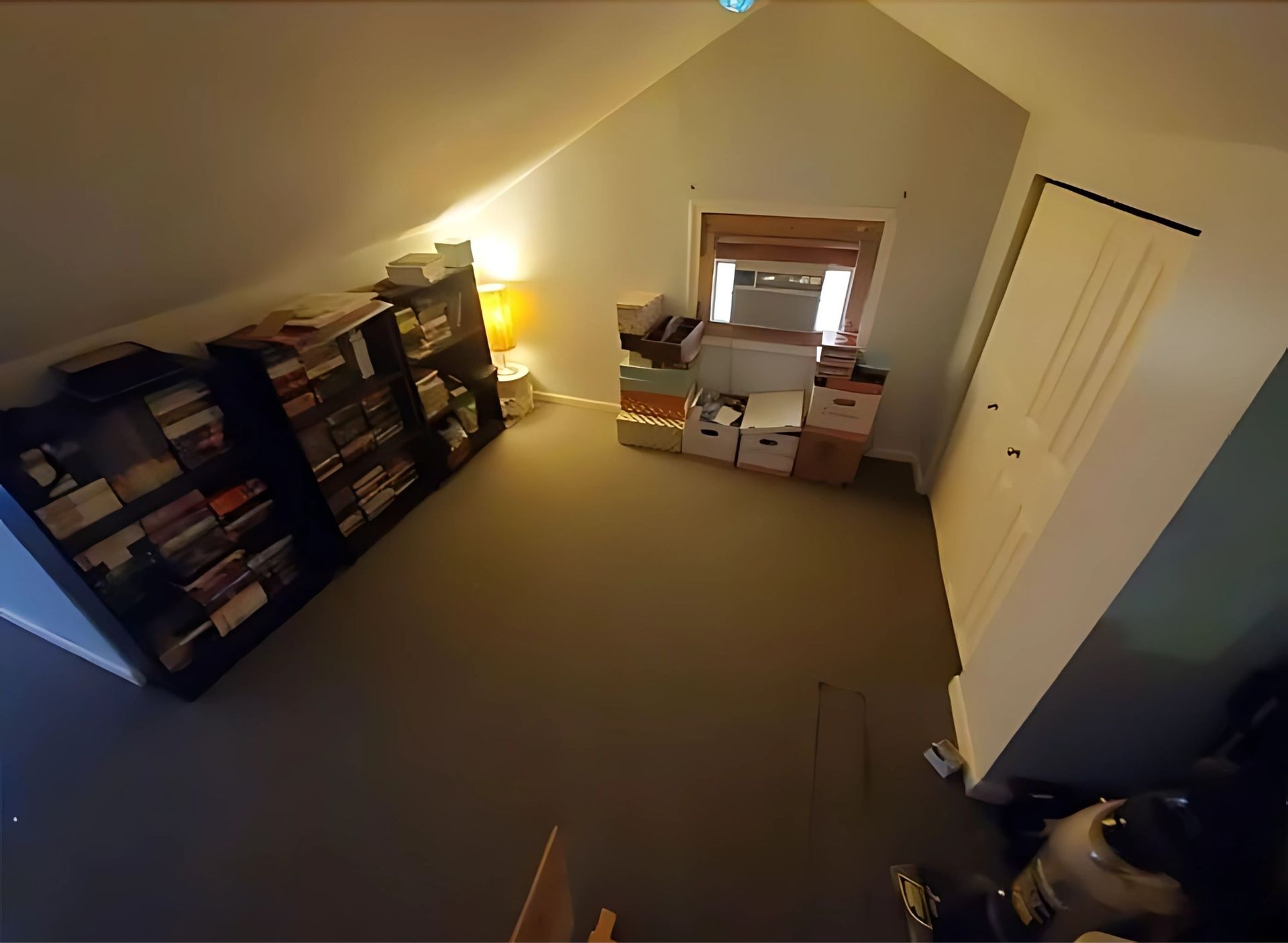 A room with a lot of bookshelves and boxes on the floor