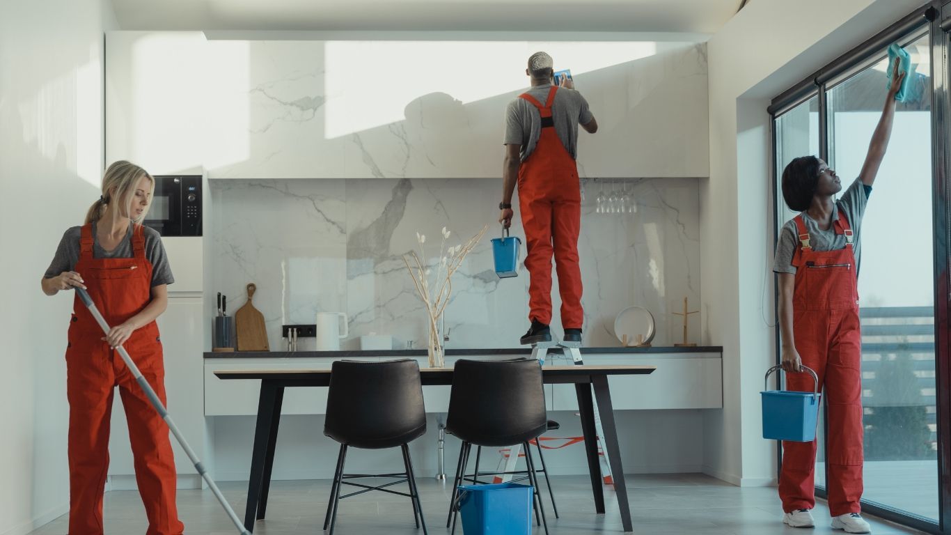 A group of people are cleaning a kitchen and dining room.
