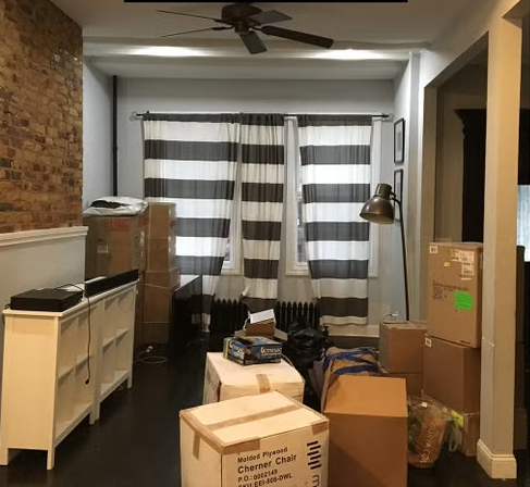 A living room filled with boxes and a ceiling fan