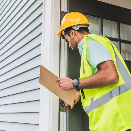 GetReadytoList | A man wearing a hard hat and safety vest is looking at a clipboard