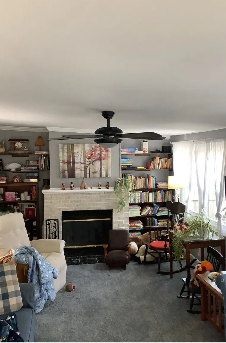 A living room with a fireplace and a ceiling fan