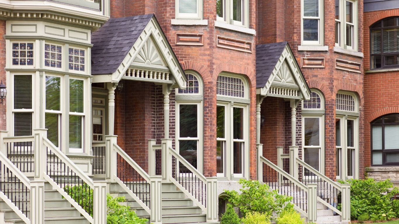 A row of brick houses with white stairs leading up to them.