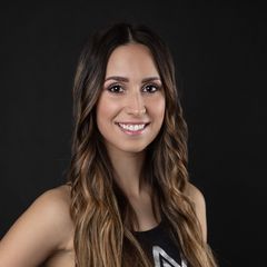 A woman with long hair is smiling in front of a black background.
