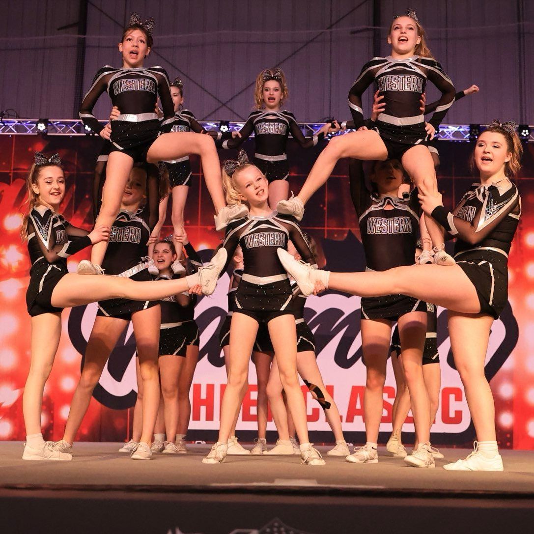 A group of cheerleaders are doing splits on a stage.