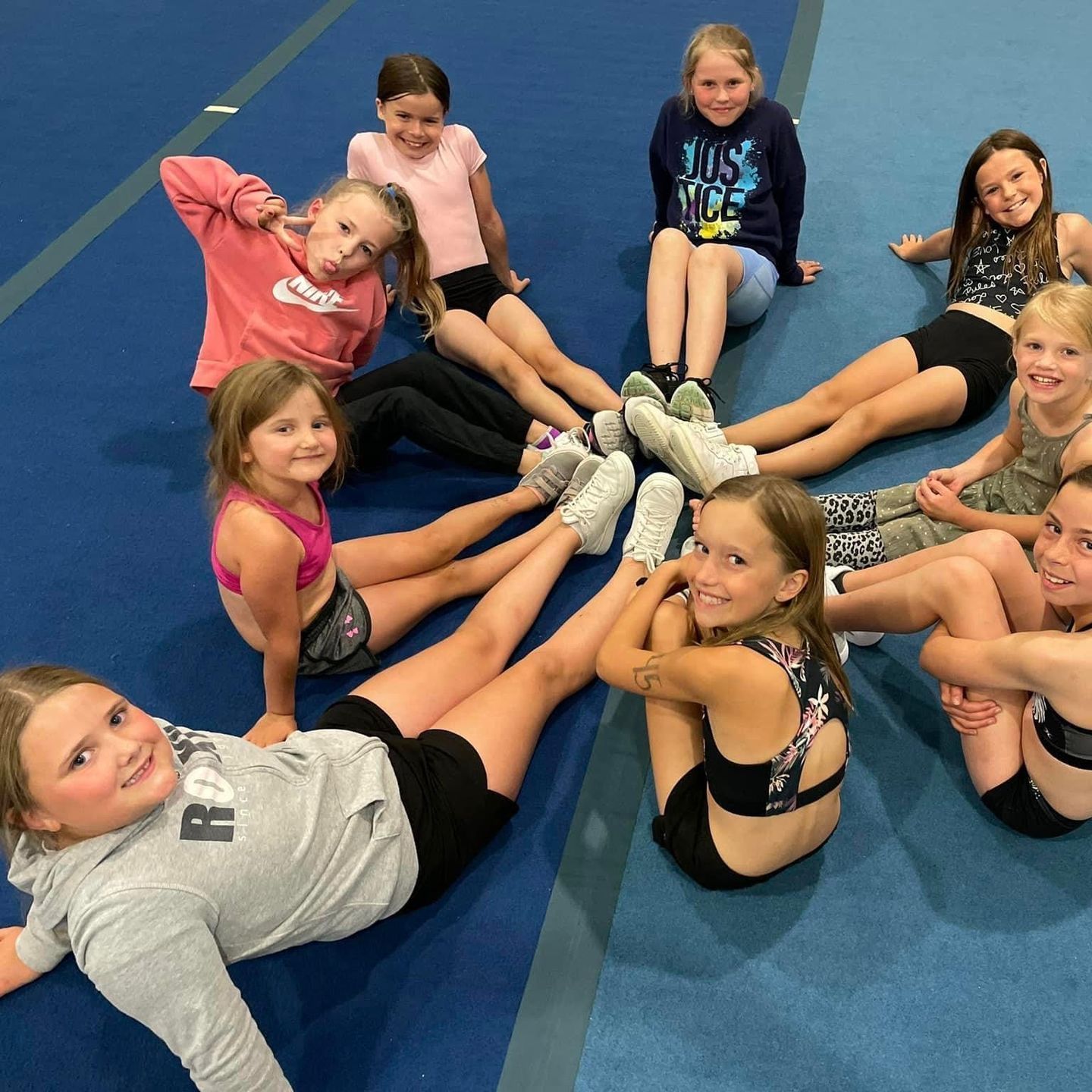 A group of young girls are sitting in a circle on the floor