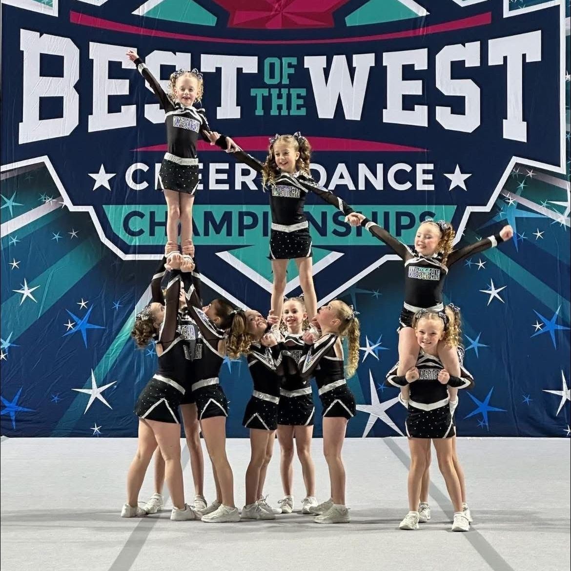 A group of cheerleaders are performing in front of a banner that says best of the west