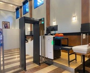 Een persoon staat voor een metaaldetector in een kamer.