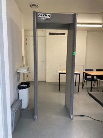 Een metaaldetector staat in een kamer naast een vuilnisbak.