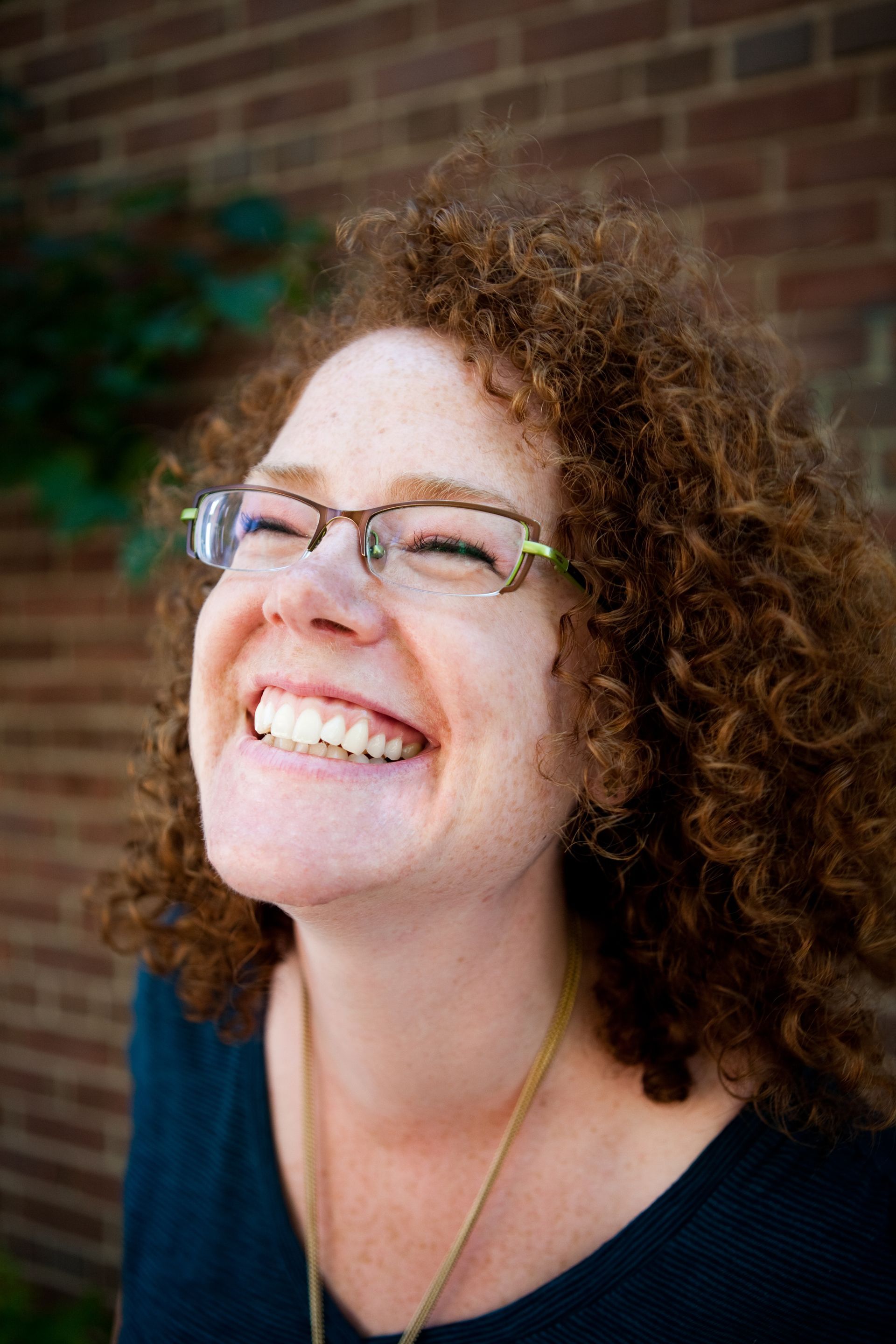 Image of Melanie McNeill smiling in front of a brick wall