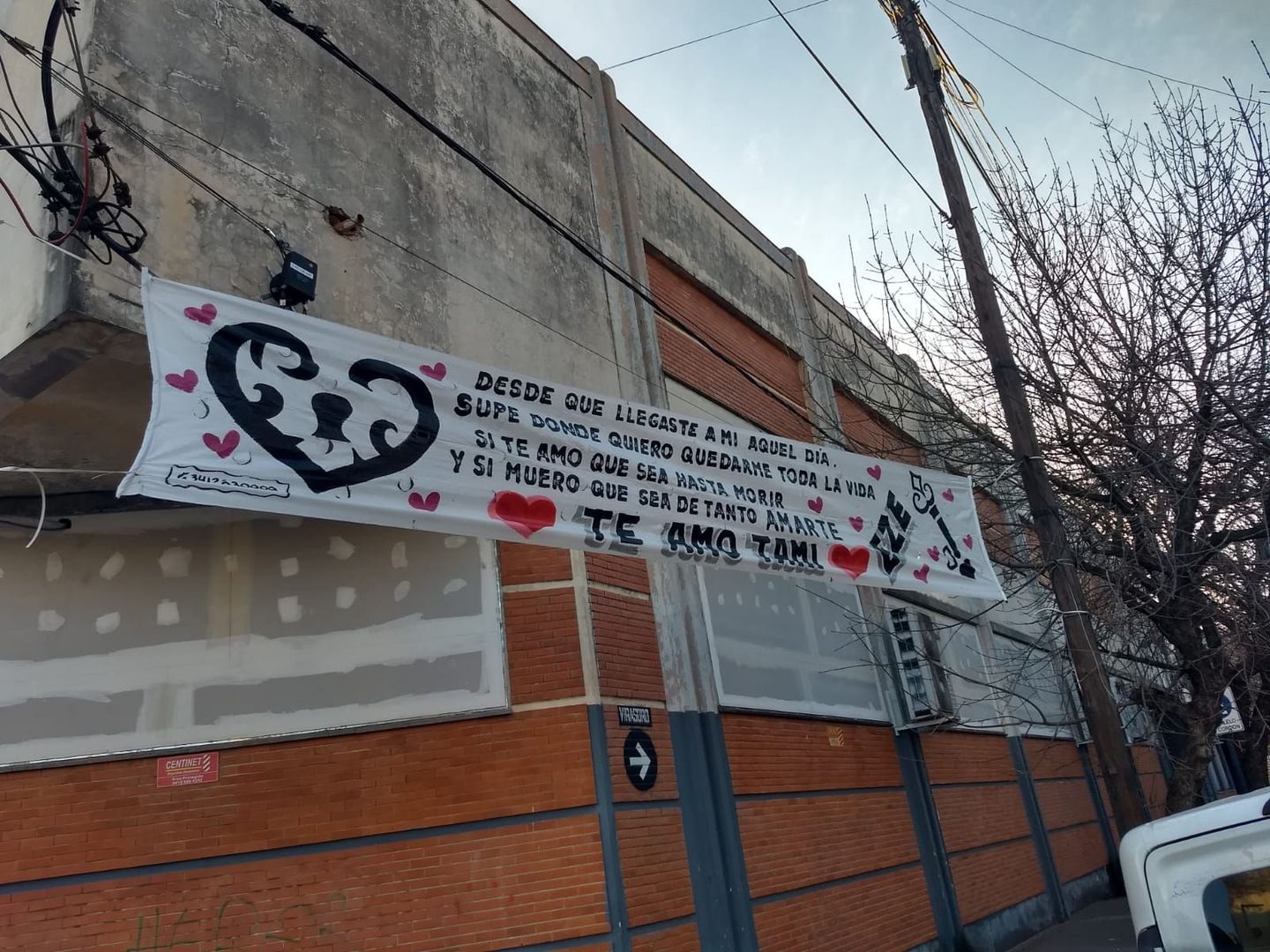 Una pancarta blanca con un corazón cuelga de un poste afuera de un edificio.