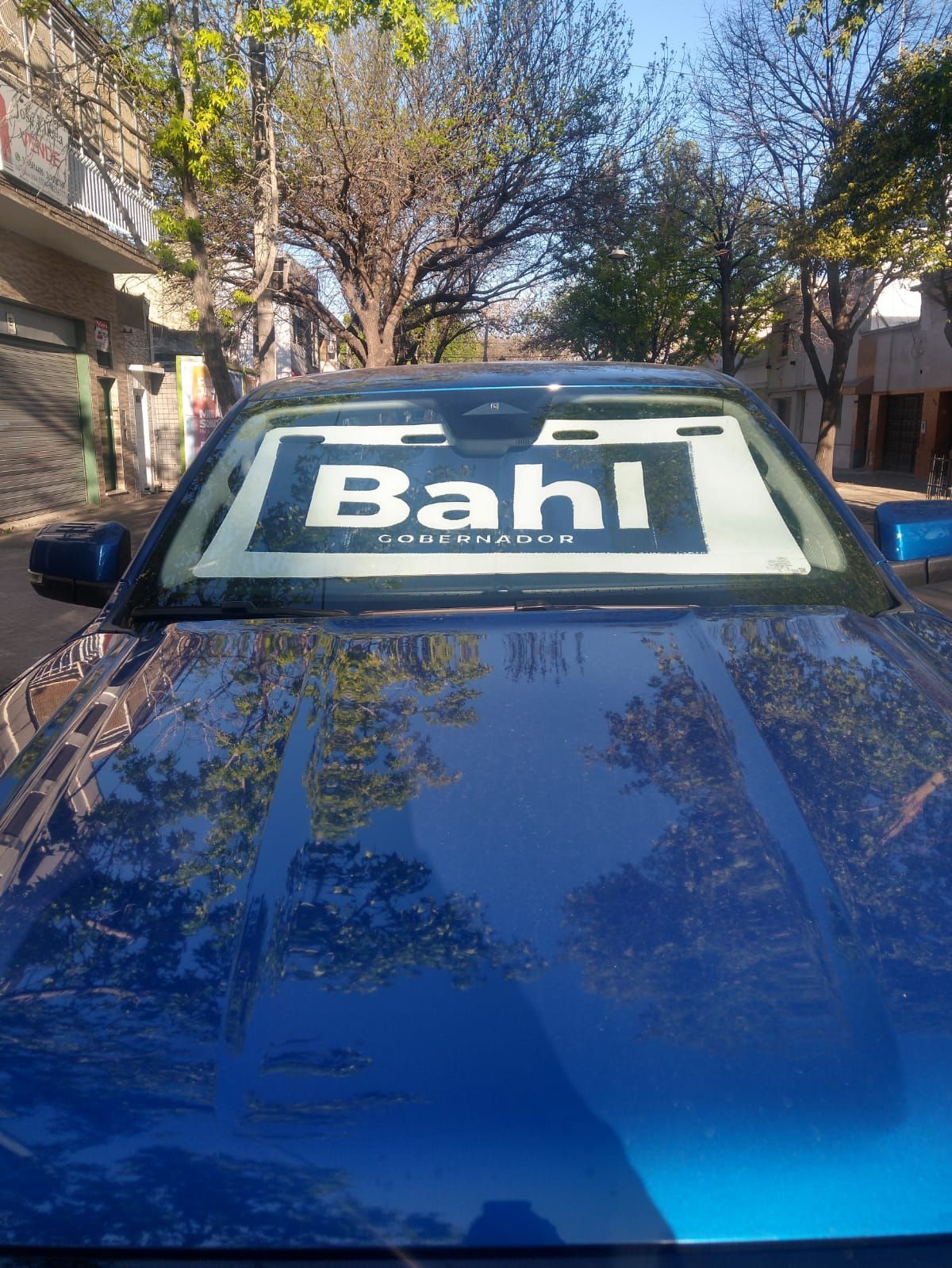 Un coche azul con un cartel parasol en el parabrisas que dice bahl.