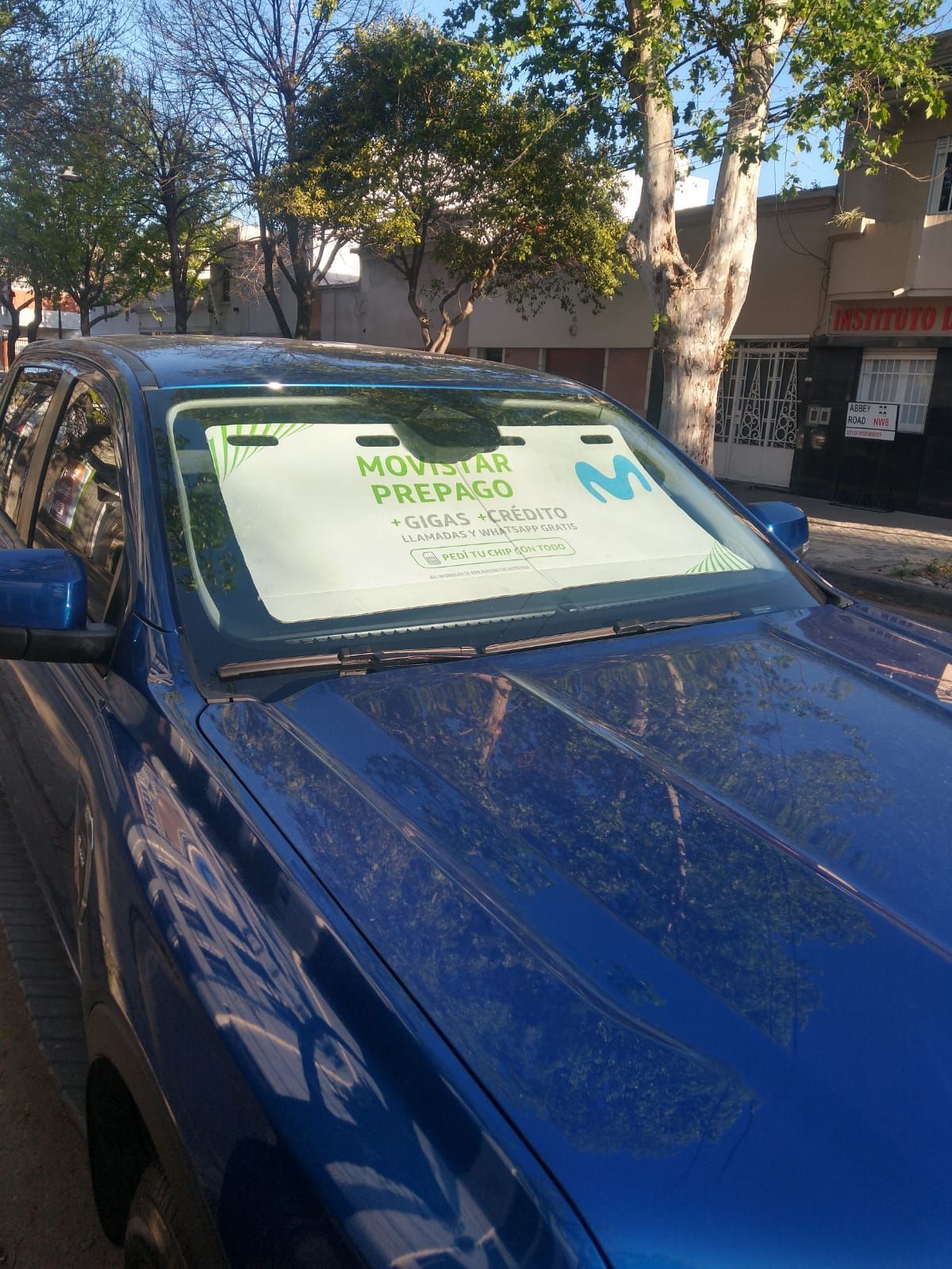 Un coche azul con un parasol en el parabrisas.