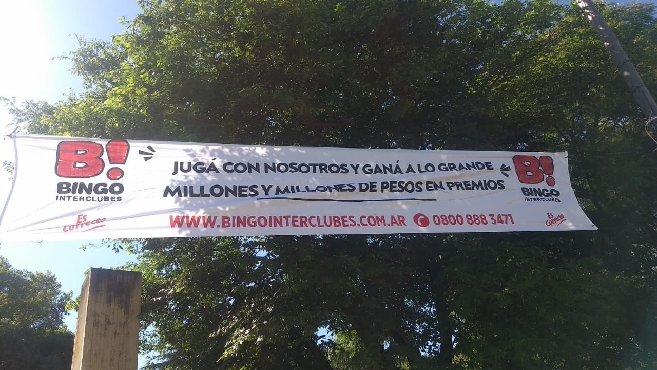 Una pancarta de bingo cuelga de un poste frente a un árbol.
