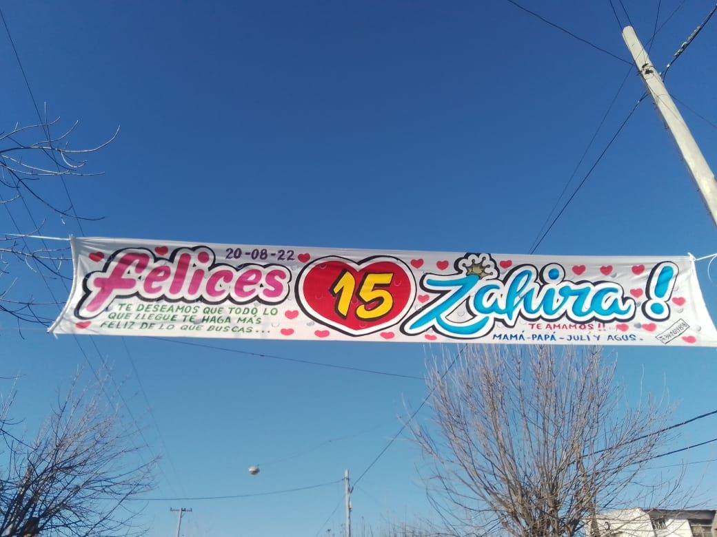 Una pancarta colgada de un cable eléctrico que dice Felices 15 Zahira