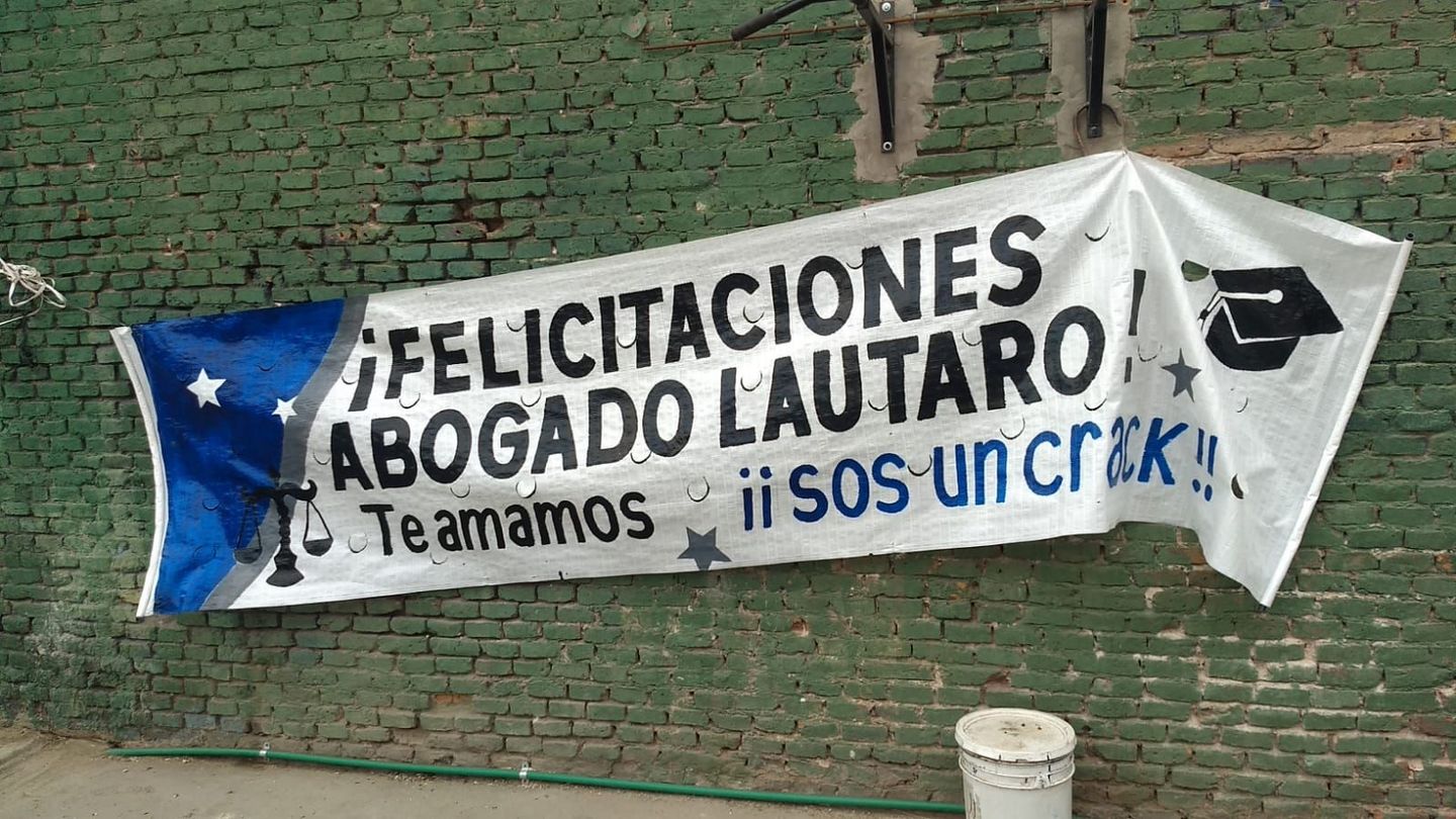 A banner hanging on a brick wall that says felicitaciones abogado lautaro