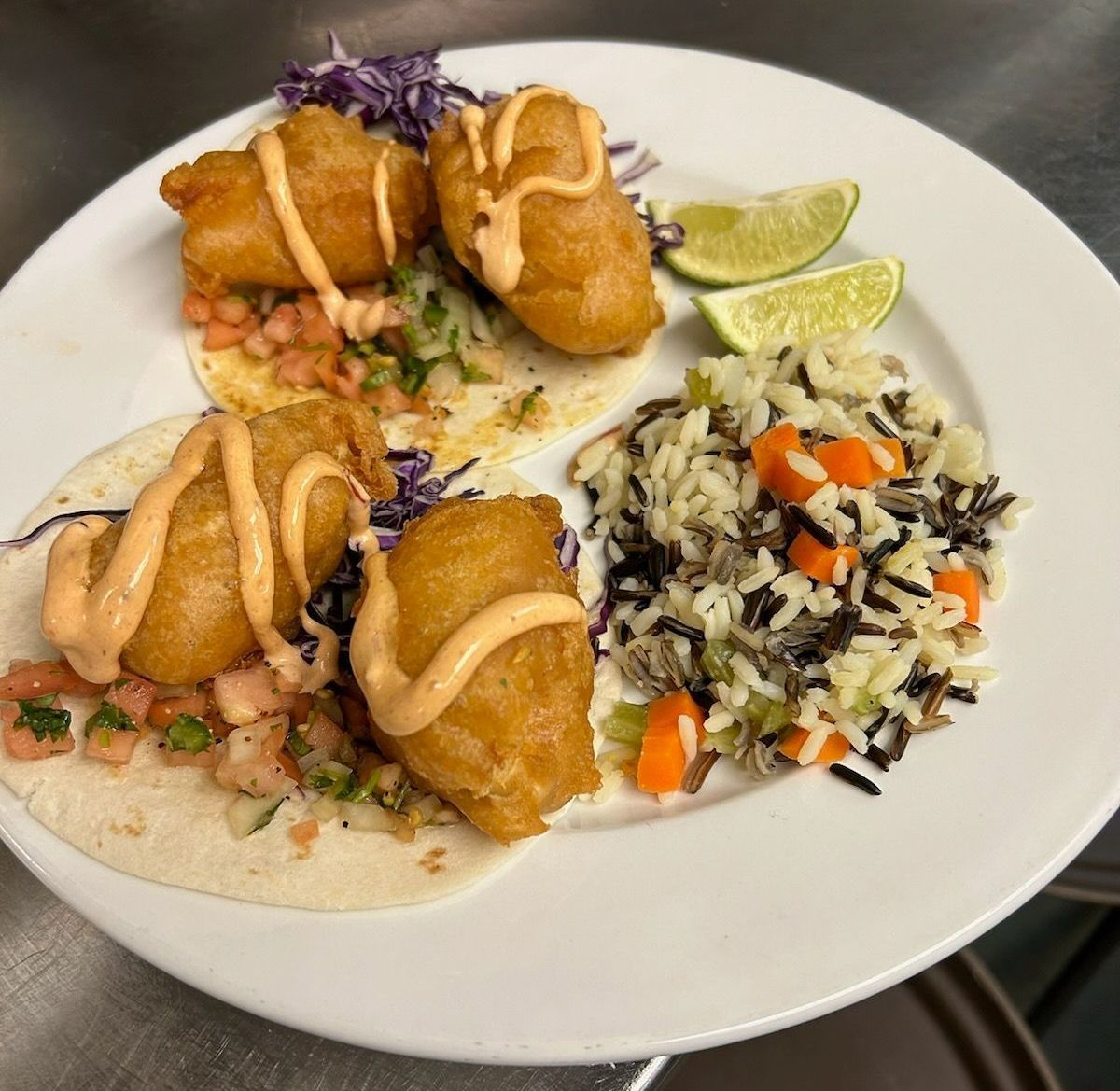 A white plate topped with fish tacos and rice